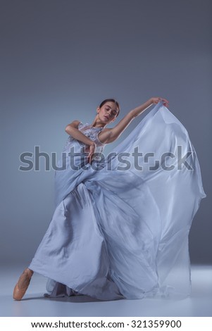 The beautiful ballerina dancing in long lilac dress on lilac background