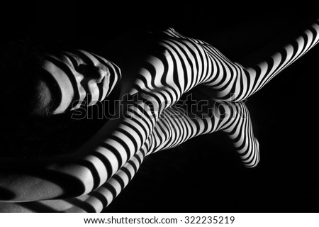 The nude woman and her reflection with black and white zebra stripes.  Black-and-white photo created with the projector