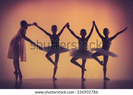 The silhouettes of little ballerinas with personal ballet teacher in dance studio posing on a orange background