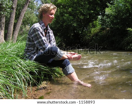 Woman rubbing feet by stream