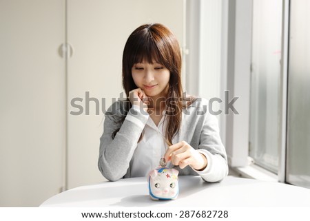 Cute Japanese business woman saving money