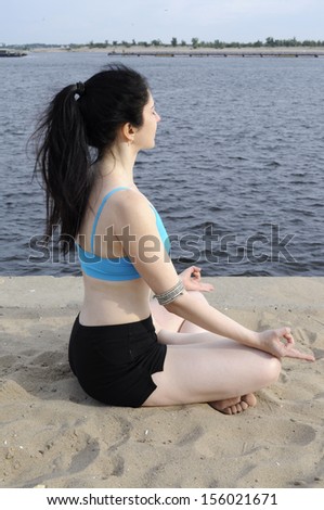 Woman sitting in lotus position on a river bank, profile view, eyes closed
