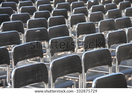 Black plastic chairs set for an outdoor event.