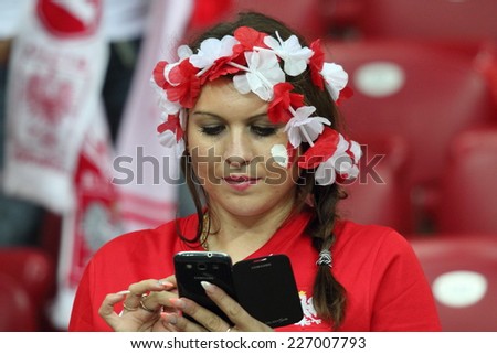 WARSAW, POLAND - OCTOBER 11, 2014: Young unidentified fan of the Polish national football team writes a text message during the UEFA EURO 2016 qualifying match of Poland vs. Germany
