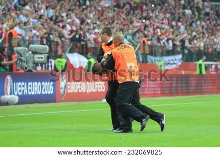 WARSAW, POLAND - OCTOBER 11, 2014: Stewards stops pitch invader after entering the field during the UEFA EURO 2016 qualifying match of Poland vs. Germany