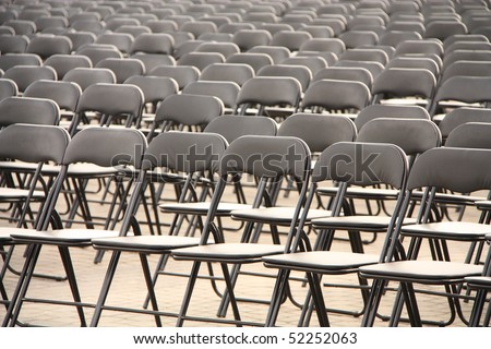 Black plastic chairs set for an outdoor event.