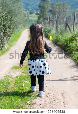 Young little girl walking alone in a country way