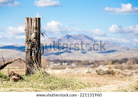 Old wood fence post with tangled barbed wire with mountains in background