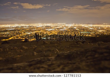 A view of a city at night from a desert lookout point.