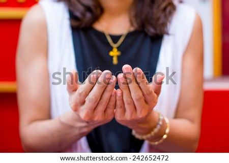 Christian believer praying to God with Cross rosary in her Neck. Focus on Hand