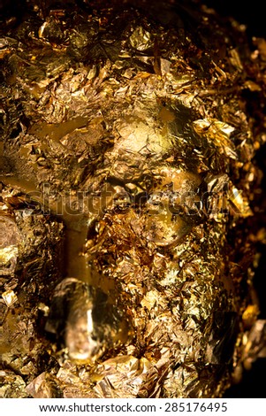 abstract Gold leaf on Buddha statue face , in the Dark tone, Religion concept