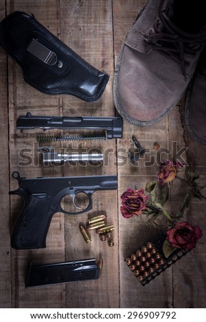 Still Life Disassembled handgun ,Bullet ,Boots, Rose on wood floor.