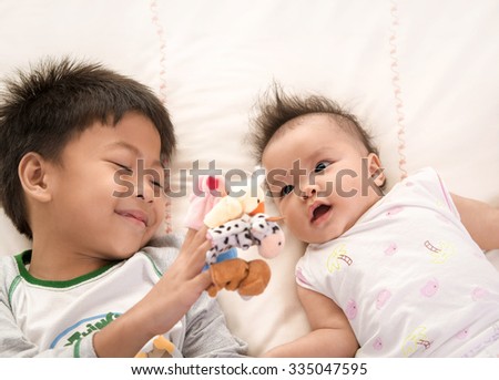 Asian boy playing  finger puppets for his sister , asian family