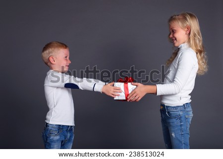 Christmas photo with small children dressed in jeans and a white sweater smiles and holding a box with a gift,gives a gift,make a surprise