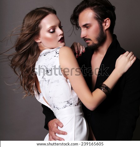 Fashion studio photo of sexy young coupl of brown-haired woman and brunette man dressed in black and white suits like yin-yang and hugging and dancing on the floor,love,lovers,Valentines