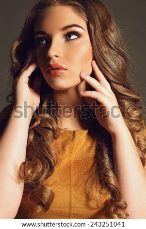 Fashion portrait of young pretty woman with blond curly lush hair and beautiful bright makeup wearing yellow dress