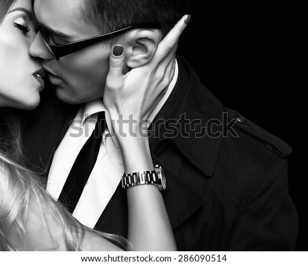Fashion photo of office romance of sexy young lovers of beautiful blond woman and handsome brunette businessman wearing in format suit,tie,glasses, they are hugging and kissing on Valentine\'s day