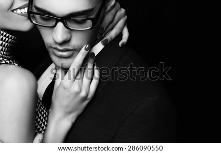 Fashion photo of office romance of sexy young lovers of beautiful blond woman and handsome brunette businessman wearing in format suit,tie,glasses, they are hugging and kissing on Valentine\'s day