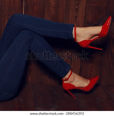 Fashion photo of woman lags wearing blue jeans and red shoes posing on the  wood background at studio - Stock Image - Everypixel