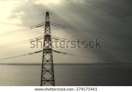 high-voltage line across the river at sunset