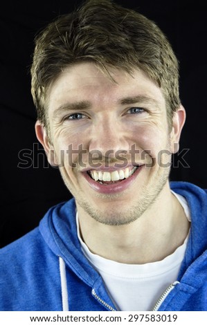 Headshot of a young man with blue eyes, white teeth and brown hair which is styled in a parting.