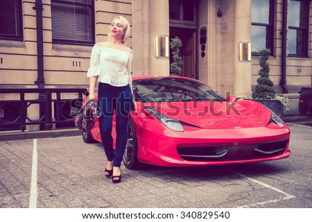 Beautiful female woman with blonde hair, and red lipstick, walking with attitude from a beautiful red coloured sports car.