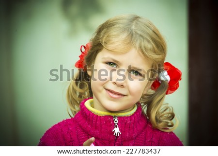 Cute little beautiful girl with green eyes smiling close-up. Adorable kid with two blond ponytail, outdoor summer portrait.