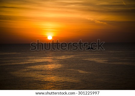 Beautiful scenic landscape and dramatic colorful sky  with orange sun rising above  Red Sea in Egypt at sunrise time. The ship sails on the sea on the background of the rising sun.