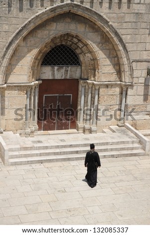 Christian priest walking to the ancient church, Jerusalem, Israel