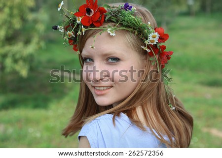 Close up portrait of Cute teen girl with a wreath of spring flowers on sunny day