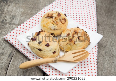 cranberry scone on the white dish, decorate with tablecloth, spoon and fork. However I attend to focus on cranberry more than decoration