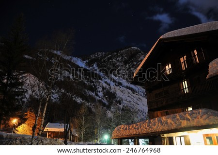Chalets covered with snow at night under a starry sky. Courmayeur Italian Alps.