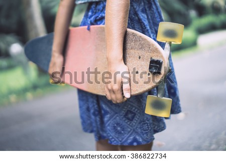 beautiful girl with skateboard. girl holding a skateboard in hands. Longboard in the hands of a girl in a dress. girl in the park with longboard in the hands of