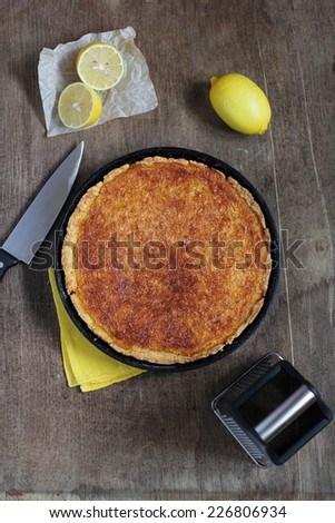 Lemon pie in pan on a background of lemons. Closeup.
