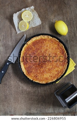 Lemon pie in pan on a background of lemons. Closeup.