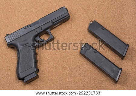 Gun and two magazines setting on a cork background