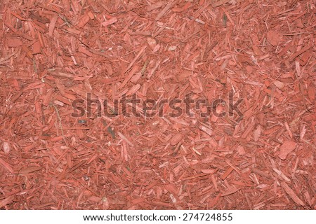 Red shredded wood mulch textured background.  Upcycled wood that is naturally dyed to help prevent weed growth and retain moisture is spread for mulch.