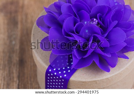 Close up of a decorated gift box.  Purple flower and ribbon up close.