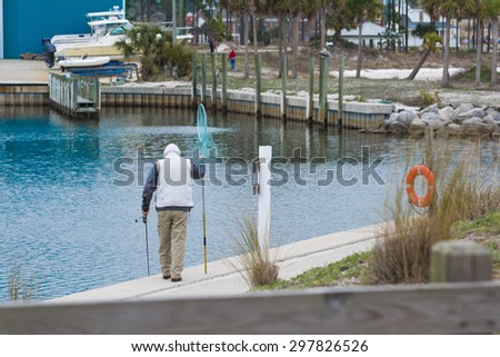 A man walks along a marina bay in Florida trying to catch fish.