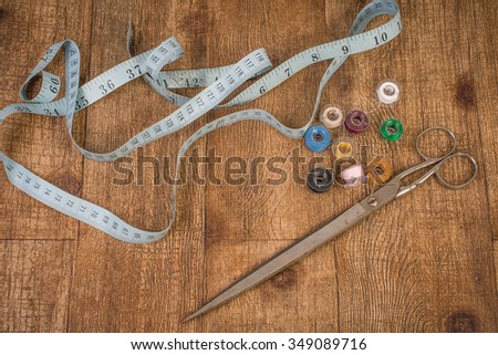 Old sewing ruler, bobbins and scissors on wood
