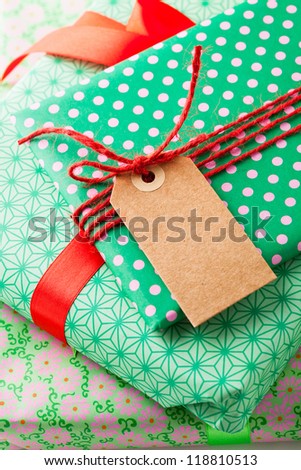 Close up of wrapped gifts with red ribbon and plain cardboard tag