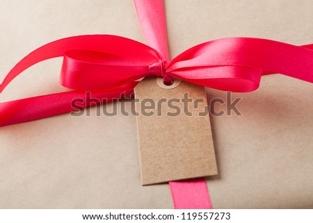 Close-up of a simple gift package with a red ribbon and simple card.