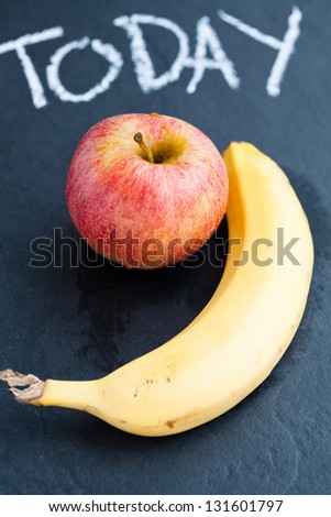 Apple and banana and word today written in chalk on dark background