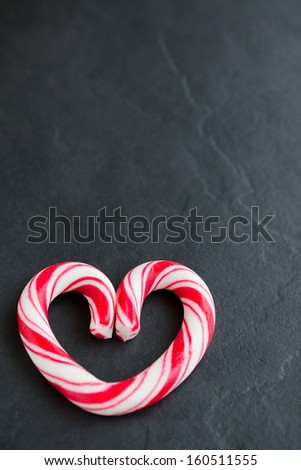 Closeup of hard candy heart with red swirls resting on dark surface