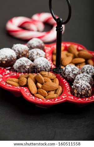 Closeup of tray of almonds and chocolate balls with hard handy heart with red swirls in background