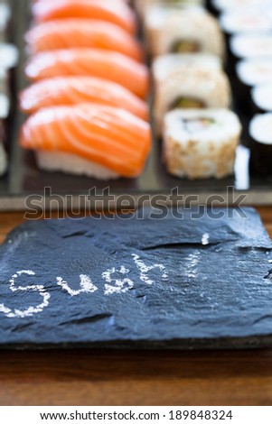 Closeup of healthy freshly prepared sushi rolls with decorative label stone with text in chalk