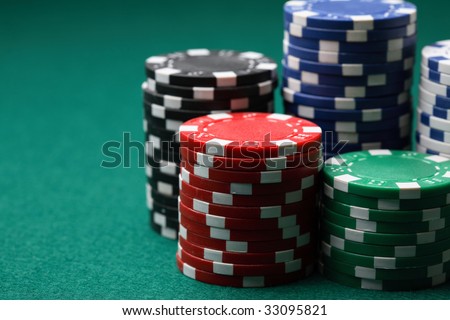 A close-up of stacks and arrangements of various colored poker chips on a green felt cloth playing surface.