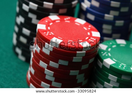 A close-up of stacks and arrangements of various colored poker chips on a green felt cloth playing surface.