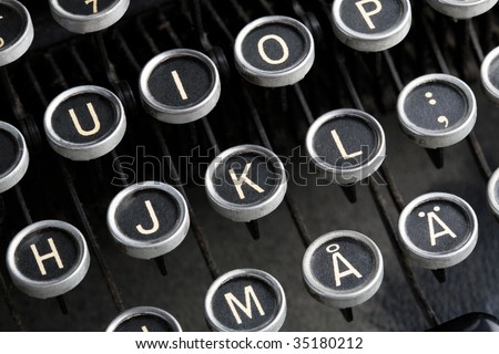 A close-up of the keys of an old, antique European language typewriter.