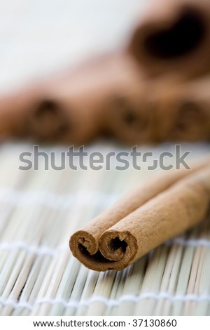 A close-up of a dry whole cinnamon stick on a table mat with additional sticks in the background.